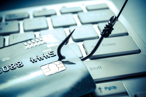 credit card phishing - piles of credit cards with a fish hook on computer keyboard